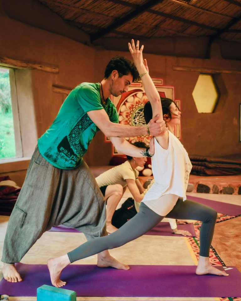 A teacher guiding a student’s alignment during practice in Cusco