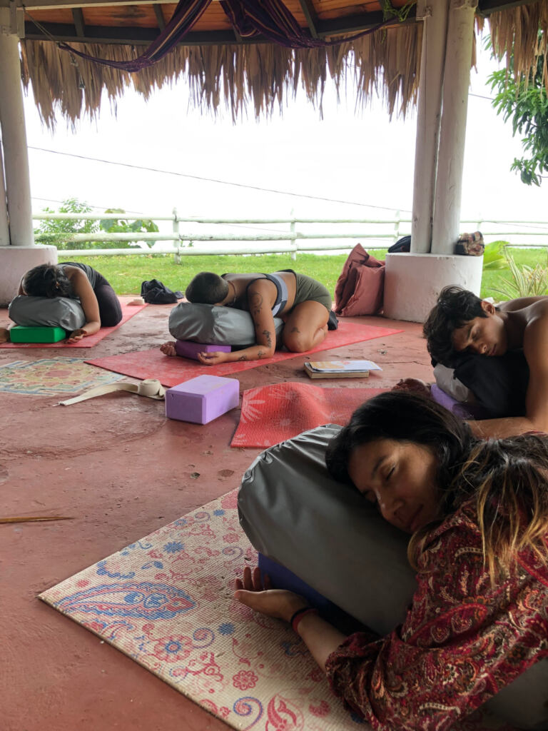 Students resting with bolsters during restorative yoga practice in Cali